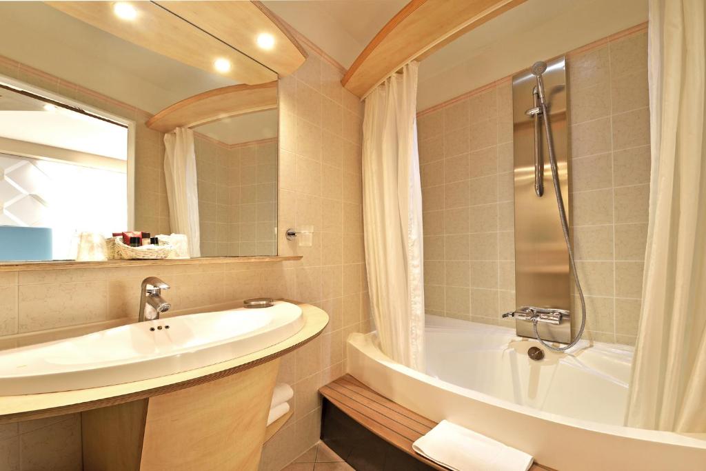 a bathroom with a sink and a tub and a shower at Hotel Tettola in Saint-Florent
