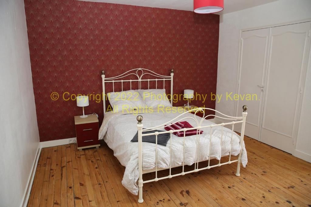 ein Schlafzimmer mit einem weißen Bett und einer roten Wand in der Unterkunft Les Chats Noirs in Pré-en-Pail