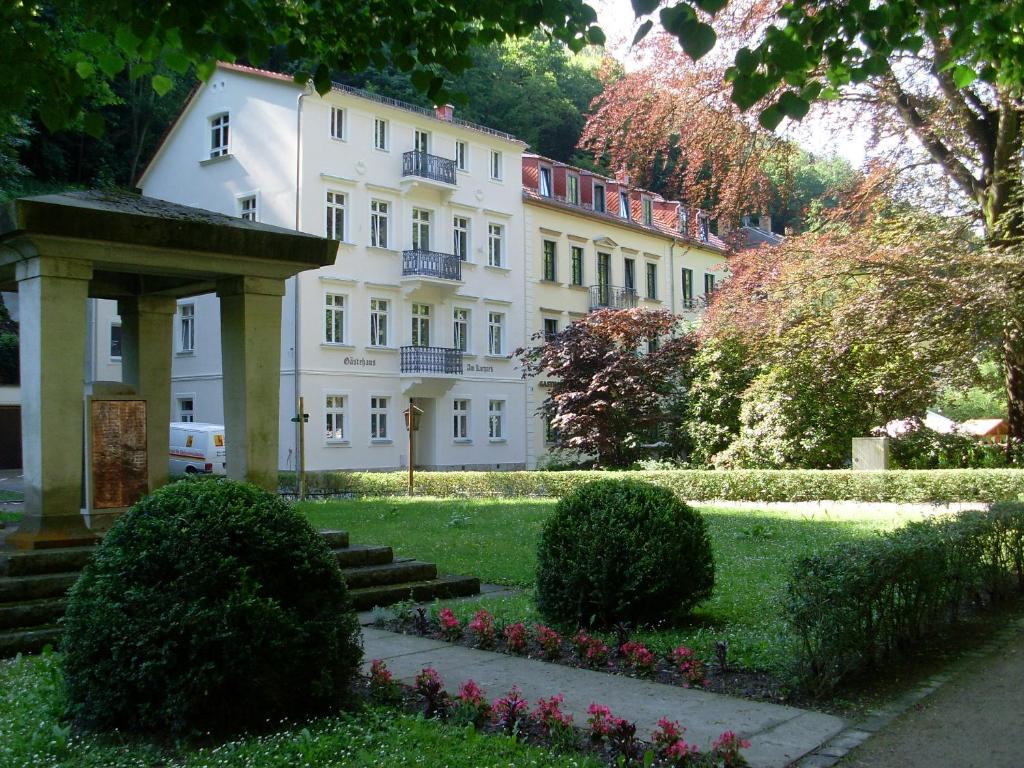 een groot wit gebouw midden in een park bij Gästehaus am Kurpark in Bad Schandau