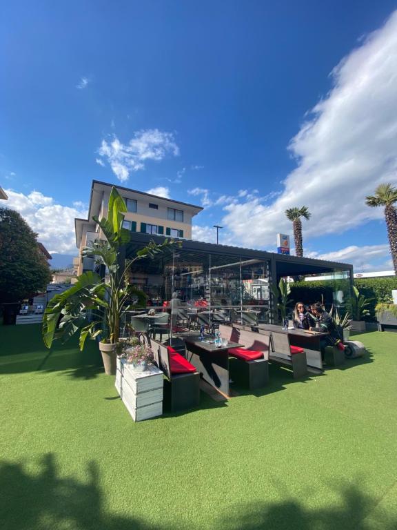 a group of people sitting at tables in a park at Hotel Aurora & Appartamenti in Nago-Torbole