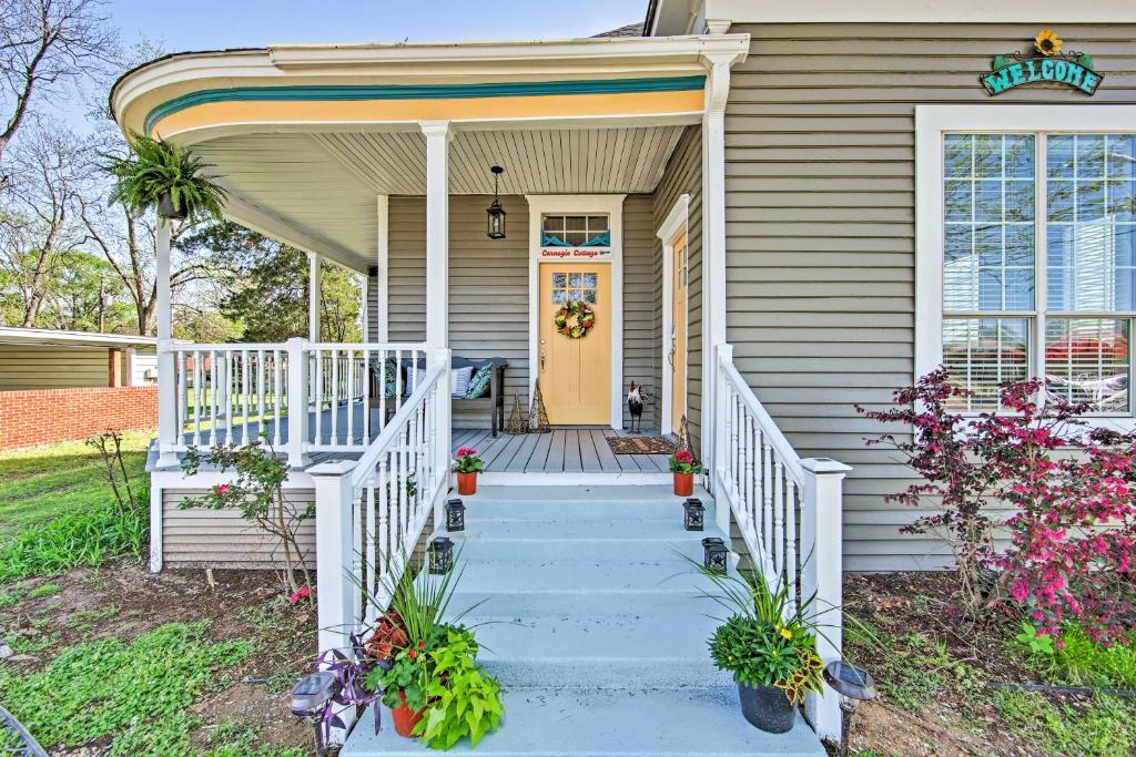 a white house with a yellow door and stairs at Renovated Carnegie Cottage - Walk to Dtwn! in Winnsboro