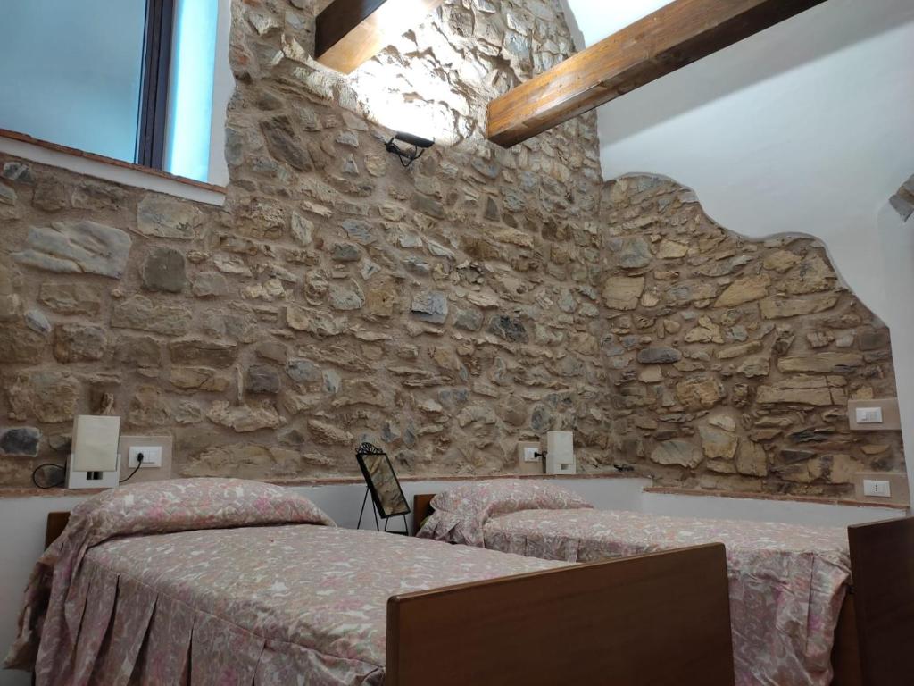 a bedroom with two beds and a stone wall at Ca'Toni in Bagnone