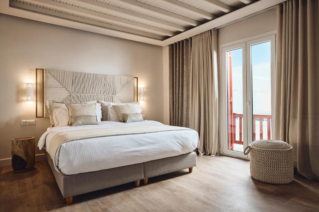 a bedroom with a large bed and a large window at AK Mykonos in Mikonos