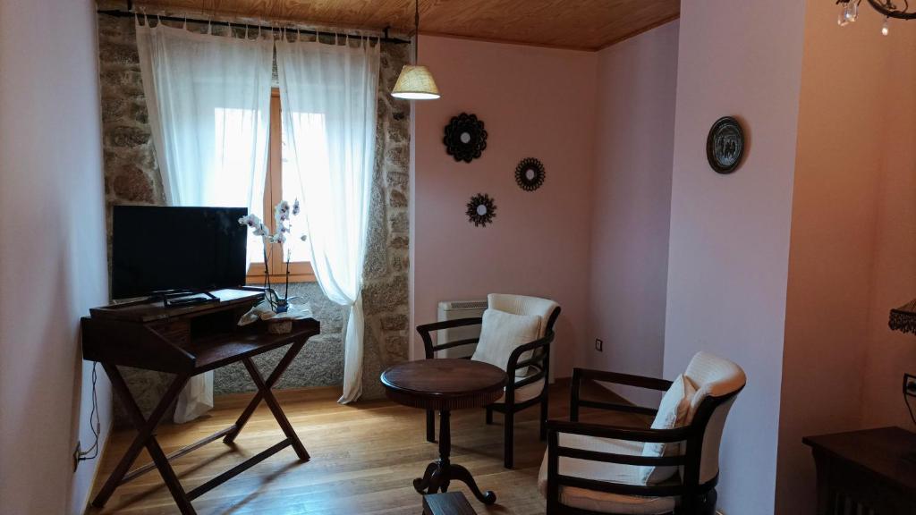 a living room with a table and chairs and a television at Casa Rosalia in Lobios