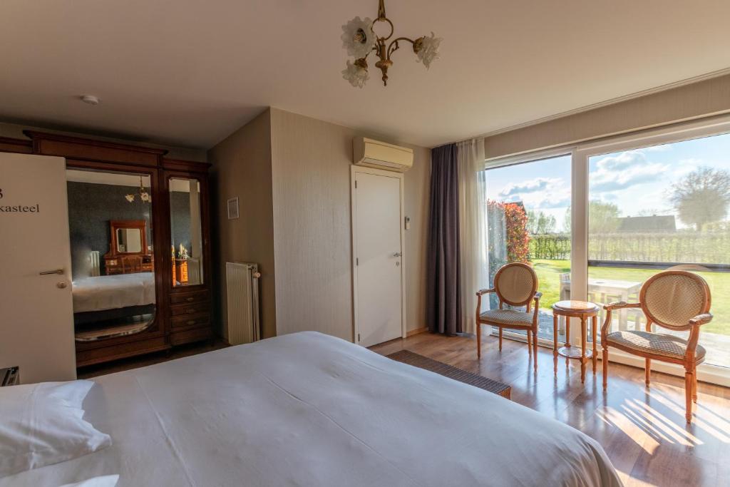 a bedroom with a bed and two chairs and a large window at Apollonia in Aalter