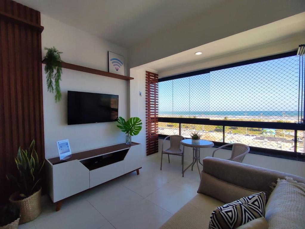 uma sala de estar com um sofá, uma televisão e uma mesa em Apartamento vista mar Atalaia todos quartos climatizados em Aracaju