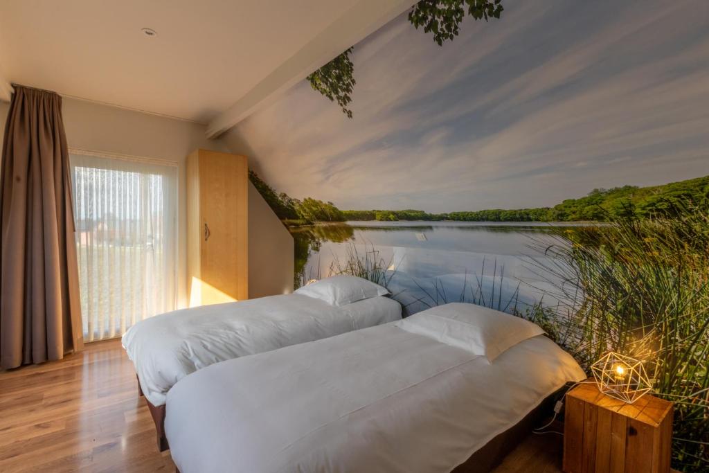 two beds in a room with a view of a lake at Apollonia in Aalter