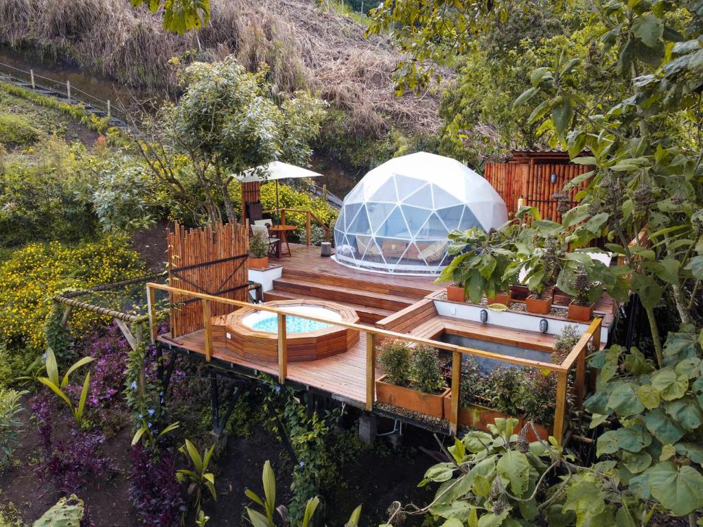 a house with a greenhouse on a deck with plants at Nazca Glamping in Villamaría