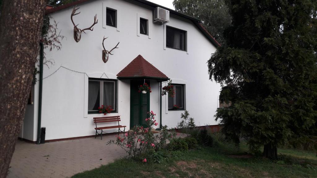 Uma casa branca com um banco à frente. em Vadászház Karád em Karád