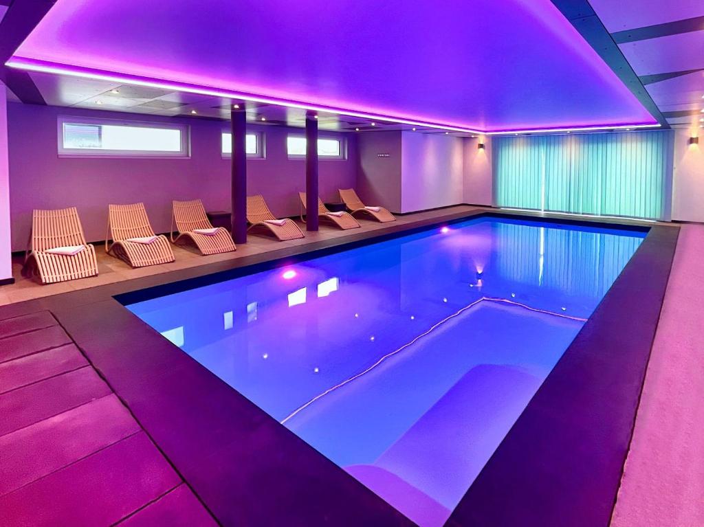 - une piscine avec des lumières violettes dans une maison dans l'établissement Villa Natica, à Butgenbach