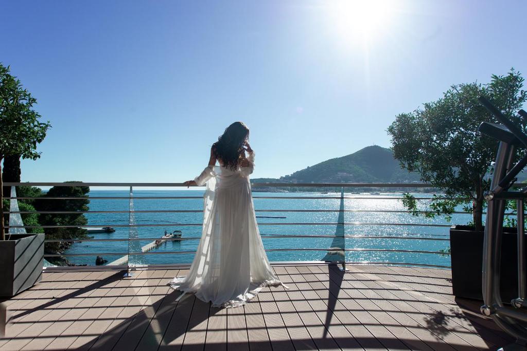a woman in a white dress standing on a boardwalk at Dukley Hotel & Resort in Budva