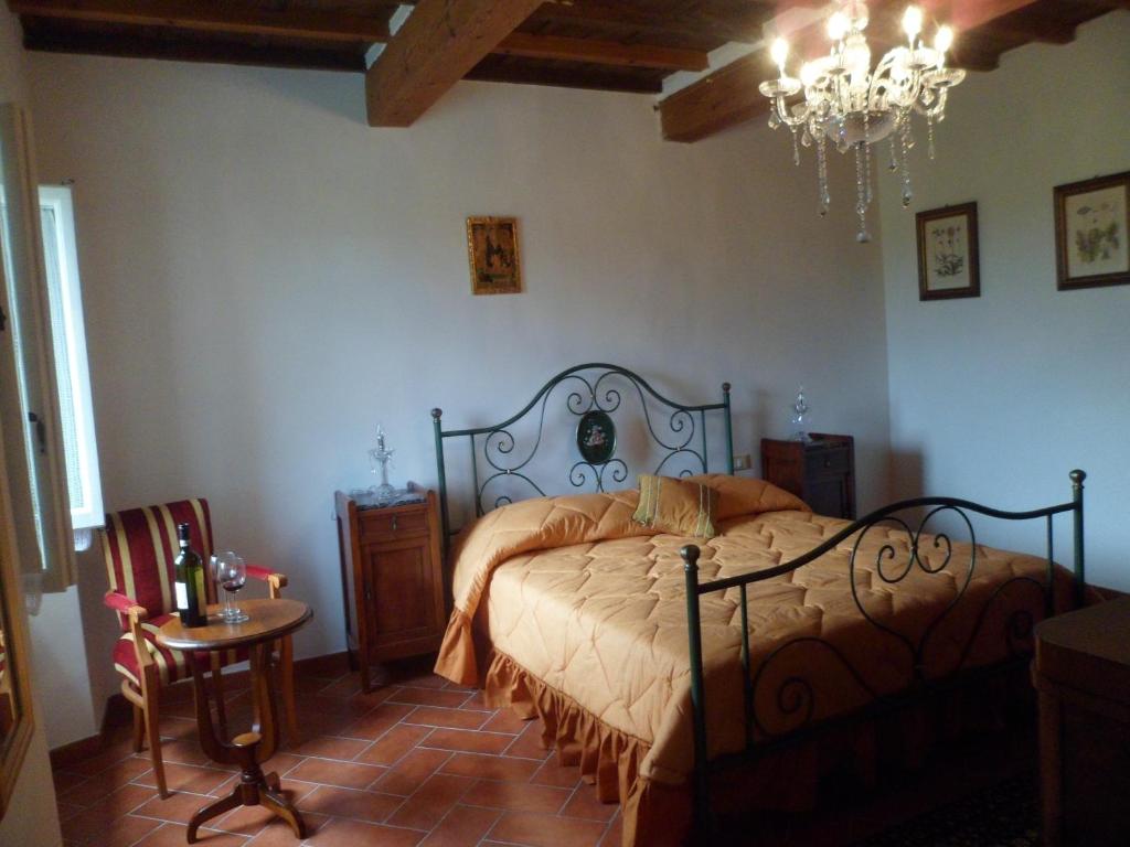 a bedroom with a bed and a chandelier at La Fiera Vecchia Apartments in Meleto