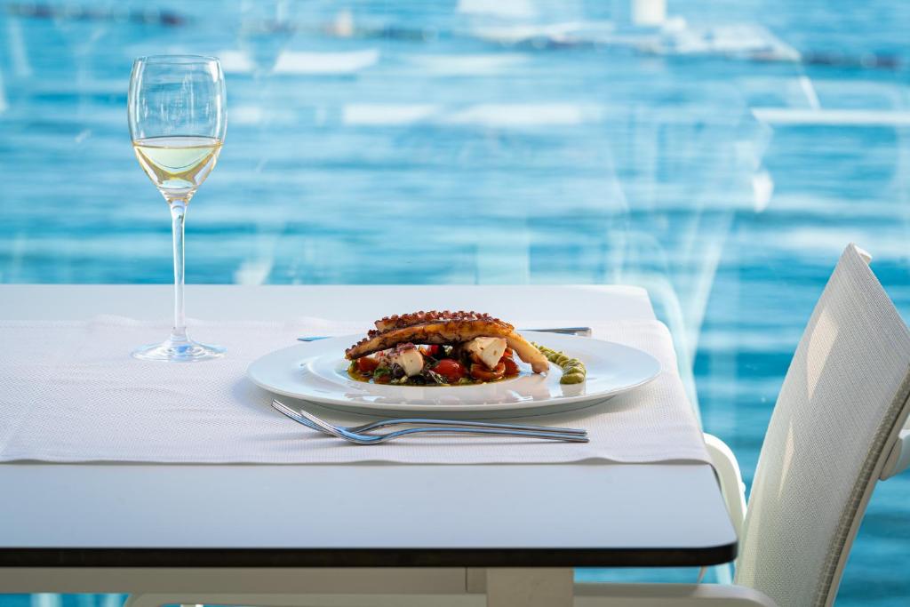 a plate of food on a table with a glass of wine at Dukley Hotel & Resort in Budva