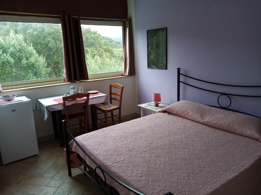 Un dormitorio con una cama y una mesa y dos ventanas. en B&B Valli Verdi, en Alghero
