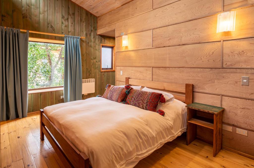 a bedroom with wooden walls and a bed with a window at Espacio Ecole Pucon in Pucón
