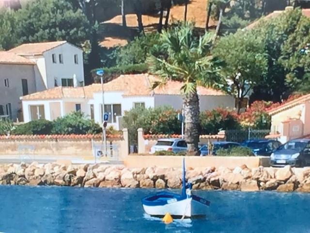 un petit bateau dans l'eau à côté d'une maison dans l'établissement ma cabane de pêcheur pieds dans l'eau - lit queen size, à Saint-Mandrier-sur-Mer