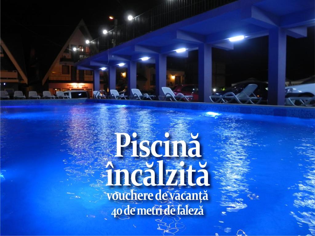 una piscina notturna con un cartello sopra di Pensiunea Iubesc Marea a Costinesti