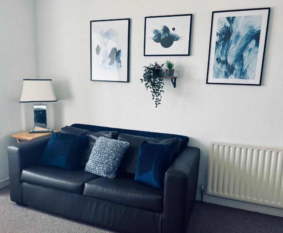 a black couch in a living room with pictures on the wall at East Linton 3 Bedroom Cottage in East Linton