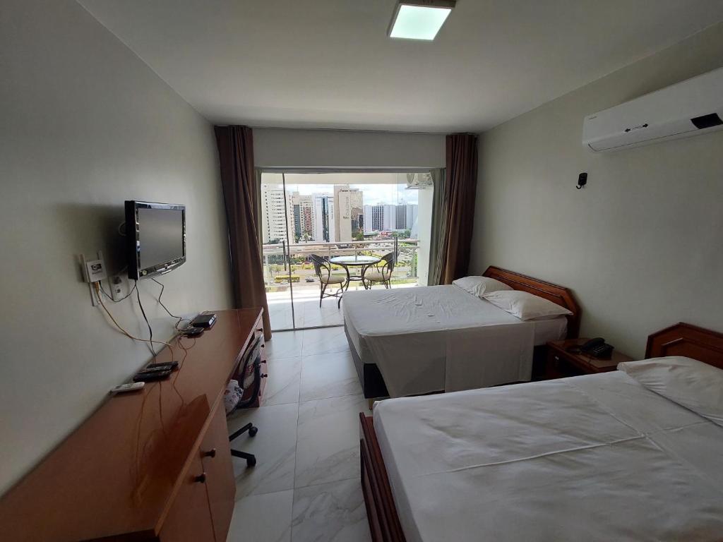 a hotel room with two beds and a television at Garvey Apart Hotel in Brasilia