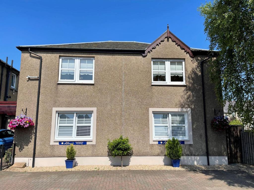 a brown brick house with white windows and potted plants at Linden Apartment in Stirling