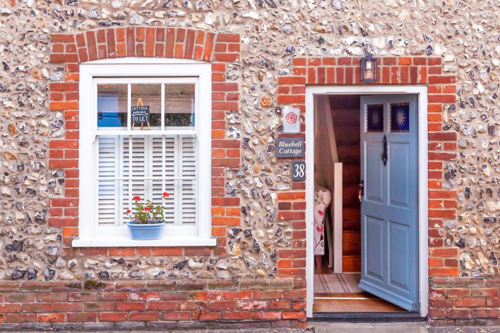 a brick house with a blue door and a window at Bluebell Cottage - Norfolk Cottage Agency in Burnham Market