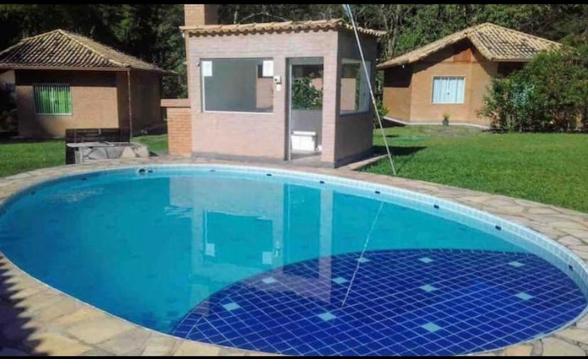 a large blue swimming pool in front of a house at Casa agradável em um condomínio na barra do sana. in Sana