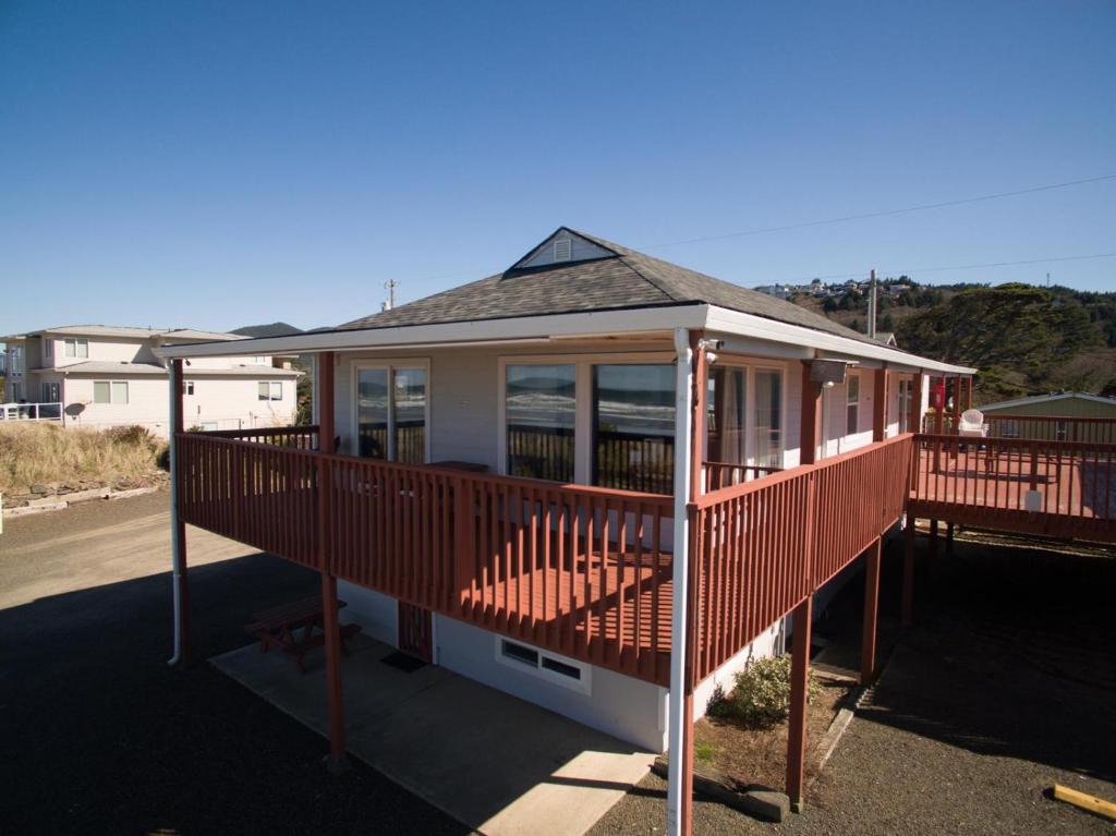 a house with a large deck with glass windows at Getaway Oceanfront Lodging in Rockaway Beach