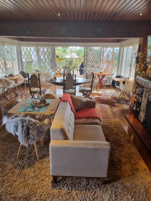 a living room with a couch and tables and chairs at Recanto dos Moinhos - Boutique Hotel in Campos do Jordão