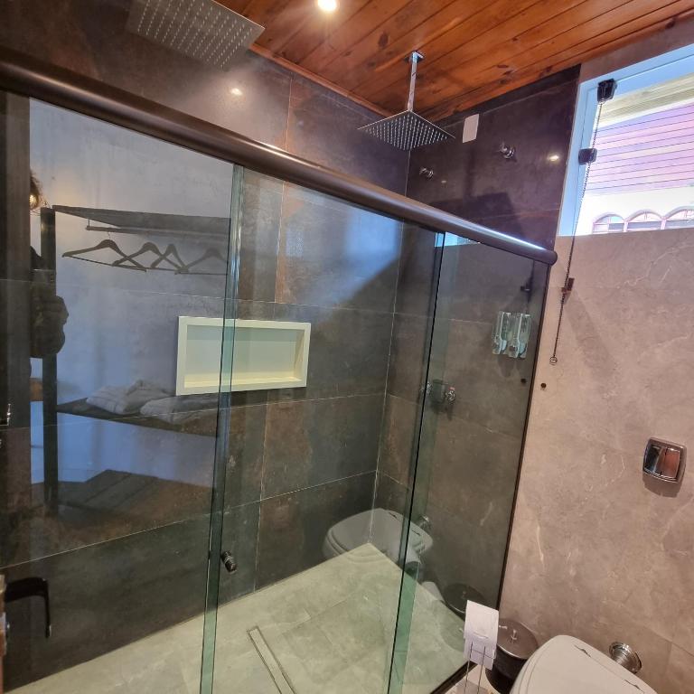 a glass shower in a bathroom with a toilet at Recanto dos Moinhos - Boutique Hotel in Campos do Jordão