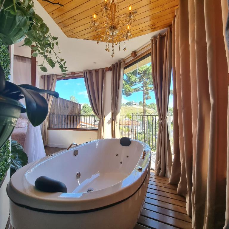 a bath tub in a room with a large window at Recanto dos Moinhos - Boutique Hotel in Campos do Jordão