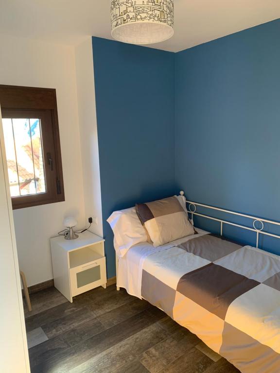 Dormitorio azul con cama y ventana en Apartamento Rural 2 Casa Bergua, en Arguis