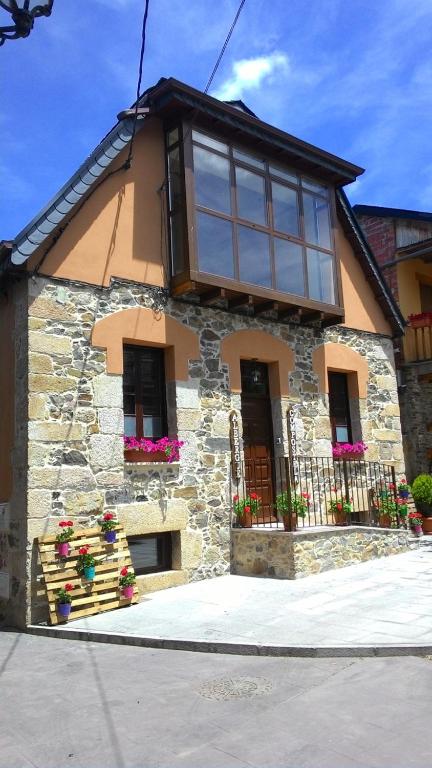 a stone house with windows and flowers in front of it at Albergue de peregrinos Compostela in Molinaseca