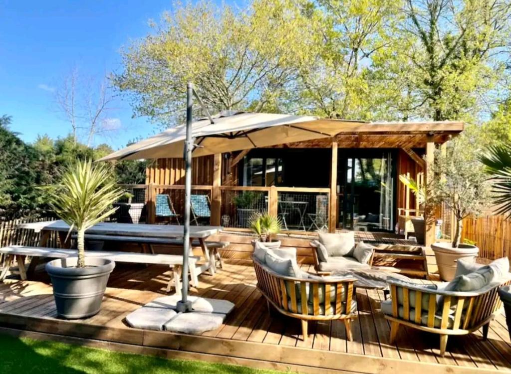 une terrasse en bois avec des chaises et un parasol dans l'établissement Cottage cosy Bassin d'Arcachon, à La Teste-de-Buch