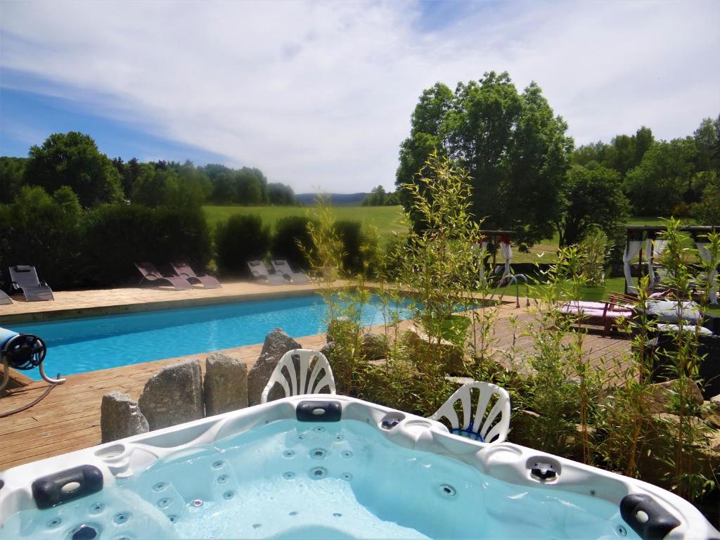 a hot tub in a yard next to a swimming pool at La maison de gilbert in Chaudes-Aigues