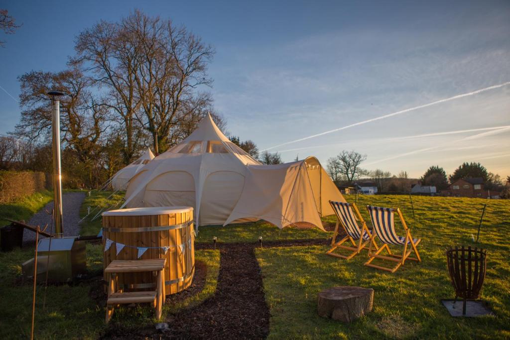 two chairs and a tent in a field at Tone valley view glamping in Wellington