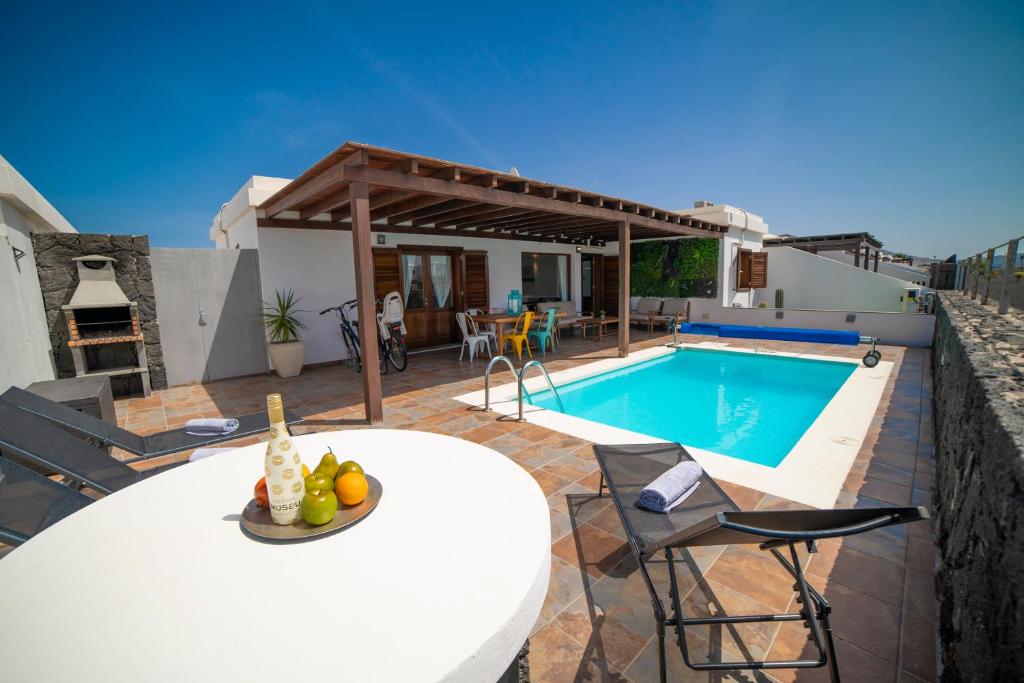 Una villa con piscina, mesa y sillas. en Villa Alba, en Playa Blanca