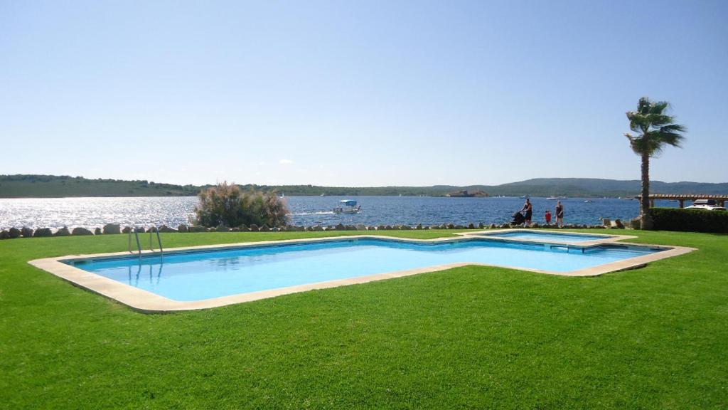 ein Schwimmbad im Gras neben einem See in der Unterkunft ES CASTELL 05 by SOM Menorca in Fornells
