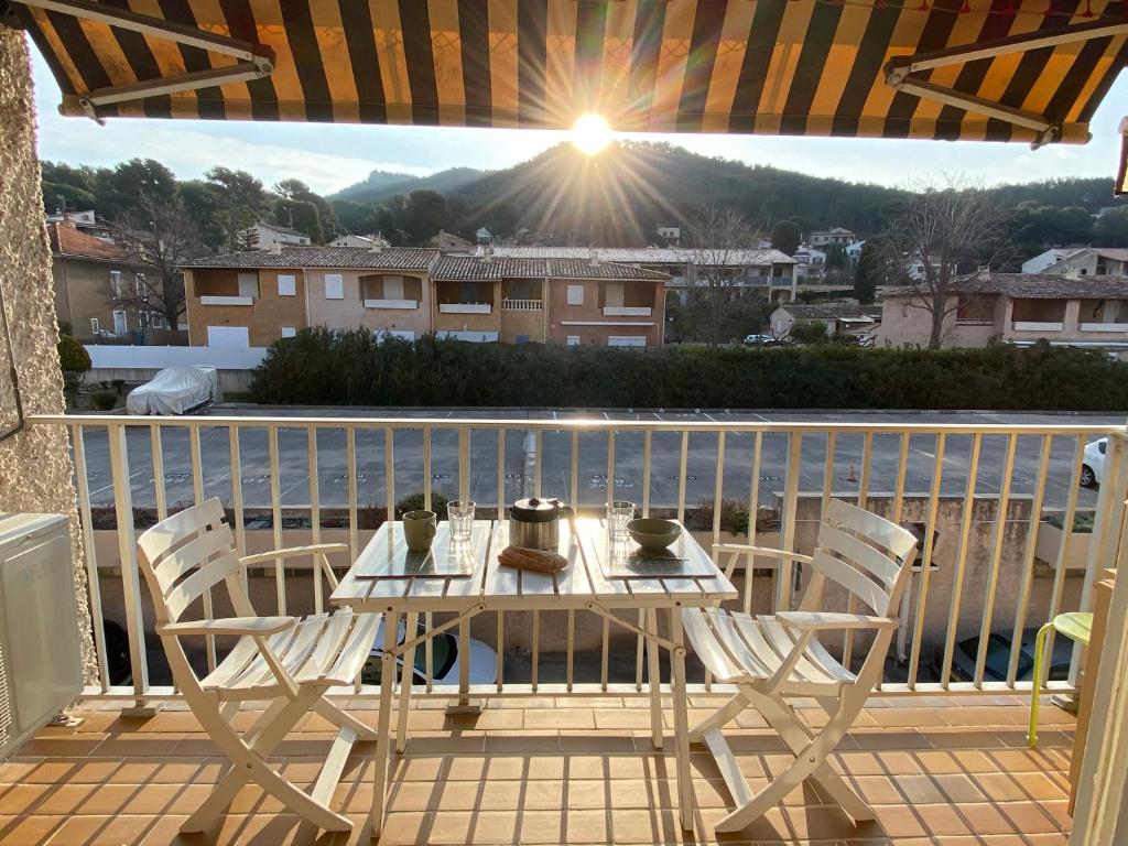 einen Tisch und Stühle auf einem Balkon mit Sonnenschein in der Unterkunft Studio La Pinède Plage à 150m Clim Place de Parking Privée in Saint-Cyr-sur-Mer