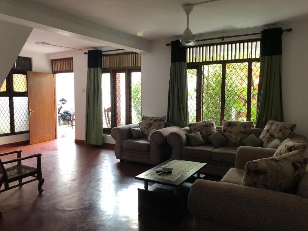 sala de estar con sofás, mesa y ventanas en Central residence Rajagiriya-Entire House, en Sri Jayewardenepura Kotte