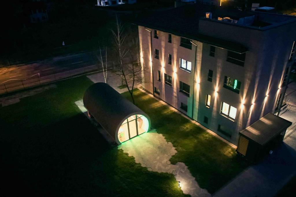 un grand bâtiment avec un feu vert devant lui la nuit dans l'établissement Acodomo Apartamenty, à Poddębice