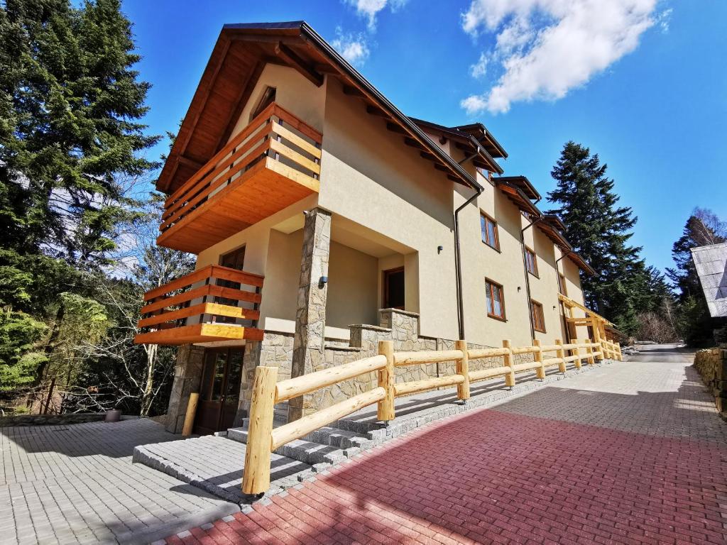 a building with a wooden fence in front of it at Agroturystyka Pod Jodłami in Żabnica