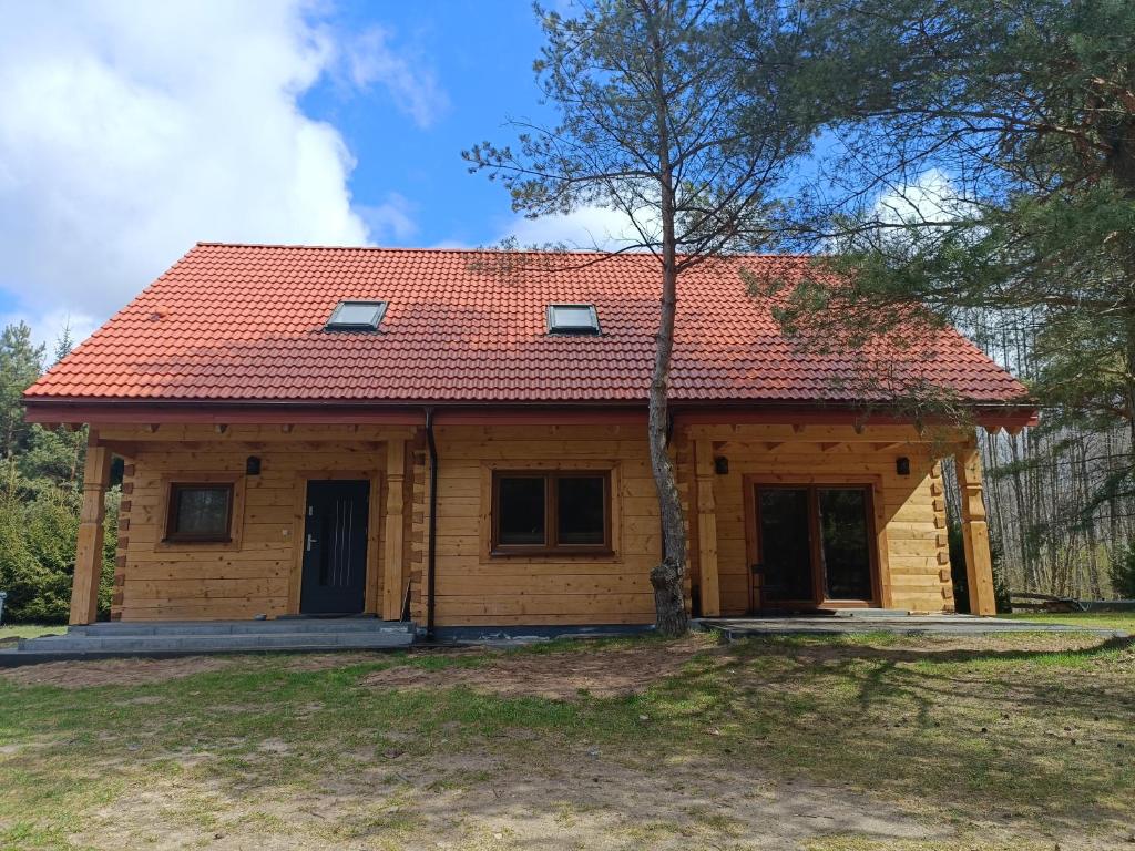 a small wooden house with a red roof at Dom z bala Dar Lasu in Szczytno