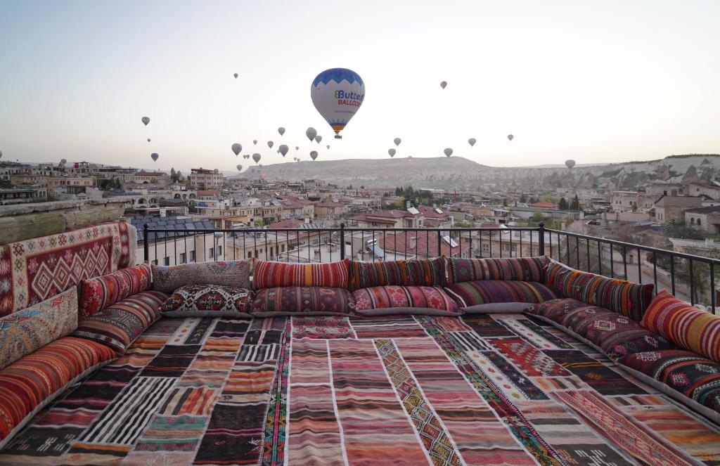 a couch on a balcony with a hot air balloon at Avlu Cave House in Goreme