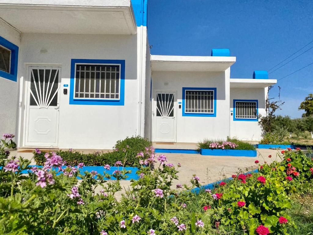 a white house with blue doors and flowers at Elgreco Apartment, at Tigaki, near the sea "3" in Tigaki