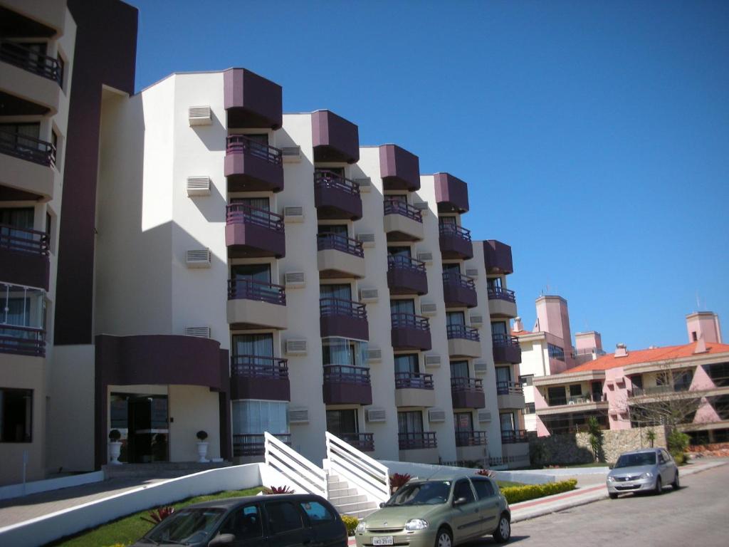 een groot gebouw met auto's geparkeerd voor het bij Condomínio Estrela do Mar in Florianópolis