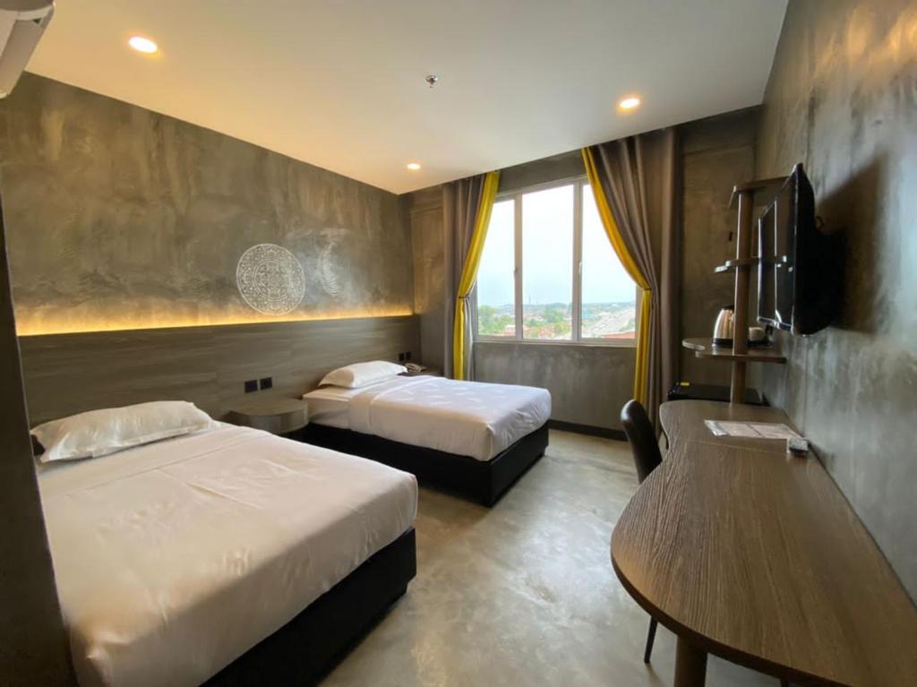 a hotel room with two beds and a window at Sri Indar Hotel & Suites in Parit Buntar