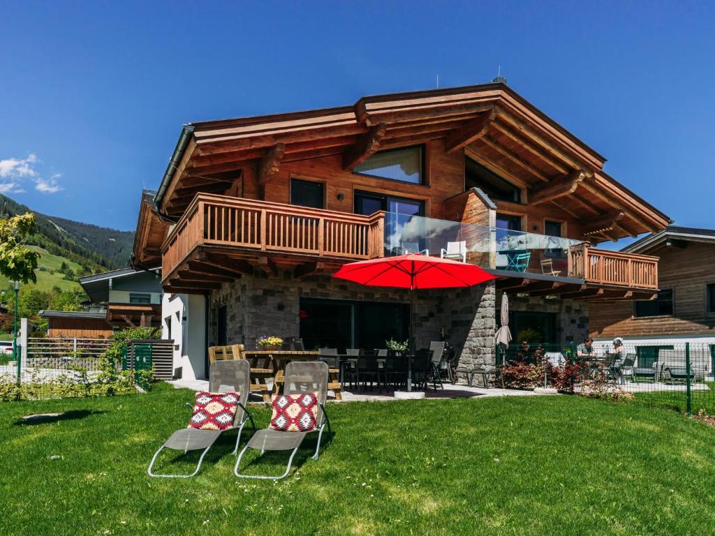 dom z dwoma krzesłami i parasolem na dziedzińcu w obiekcie Tauern Lodge XL w mieście Piesendorf