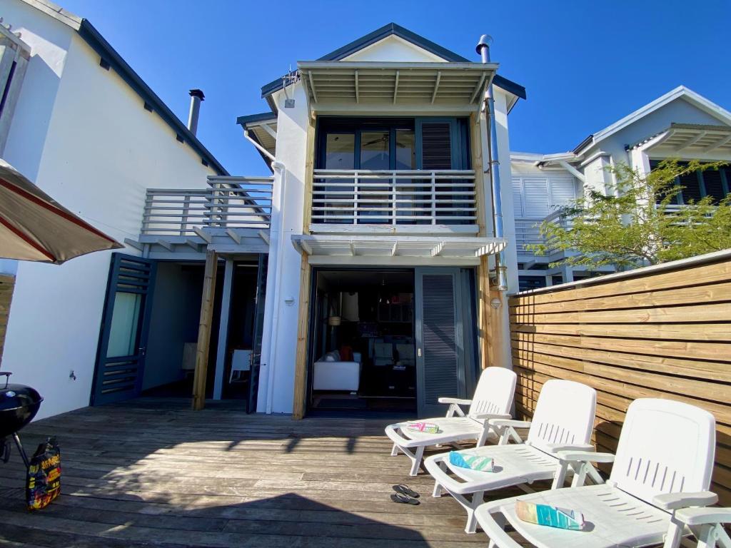 a patio with white chairs and a house at TH39 Thesen Islands in Knysna