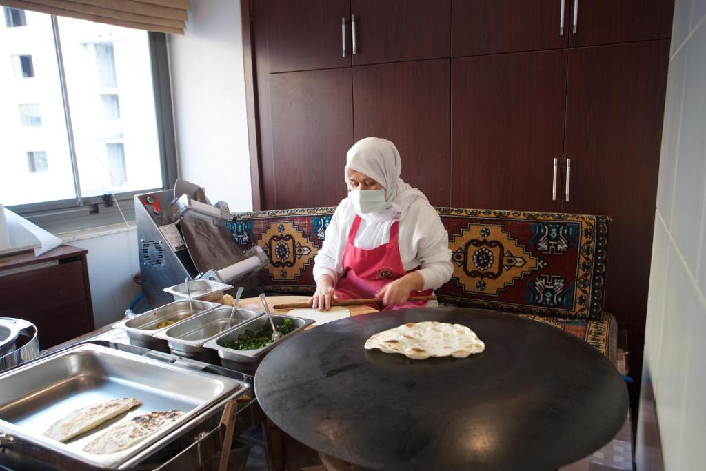 a woman in a kitchen making food on a table at Mosaic Hotel Old City -Special Category in Istanbul
