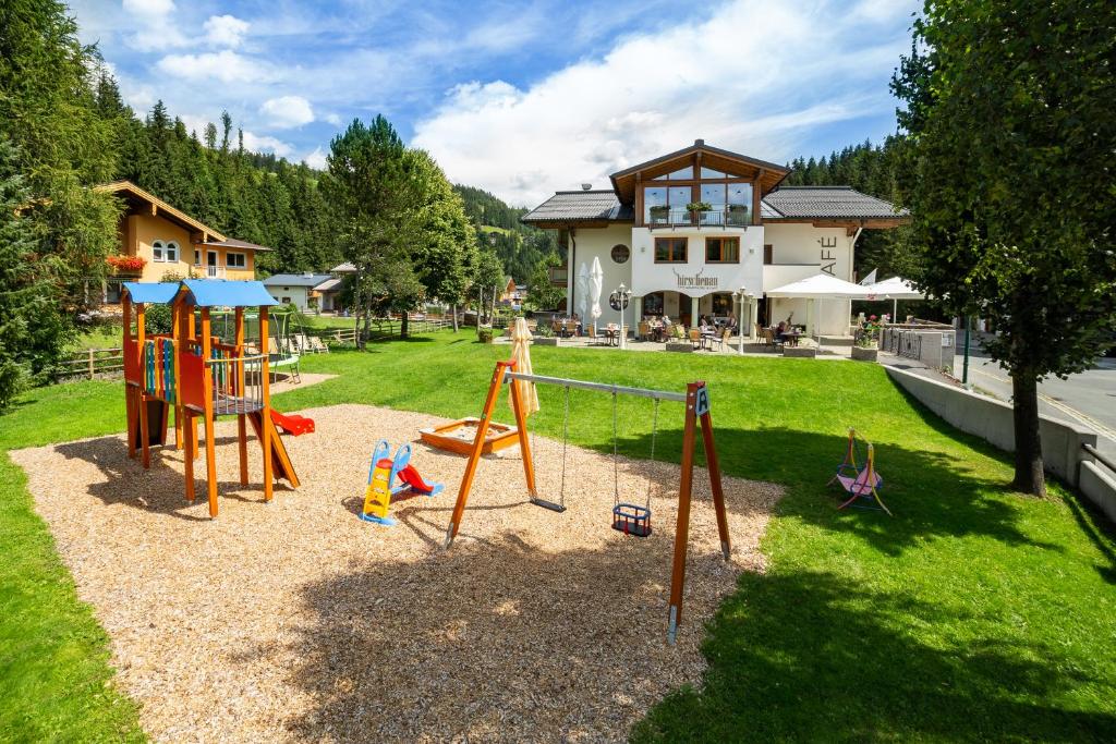 a playground in a yard in front of a house at Aparthotel Hirschenau in Filzmoos